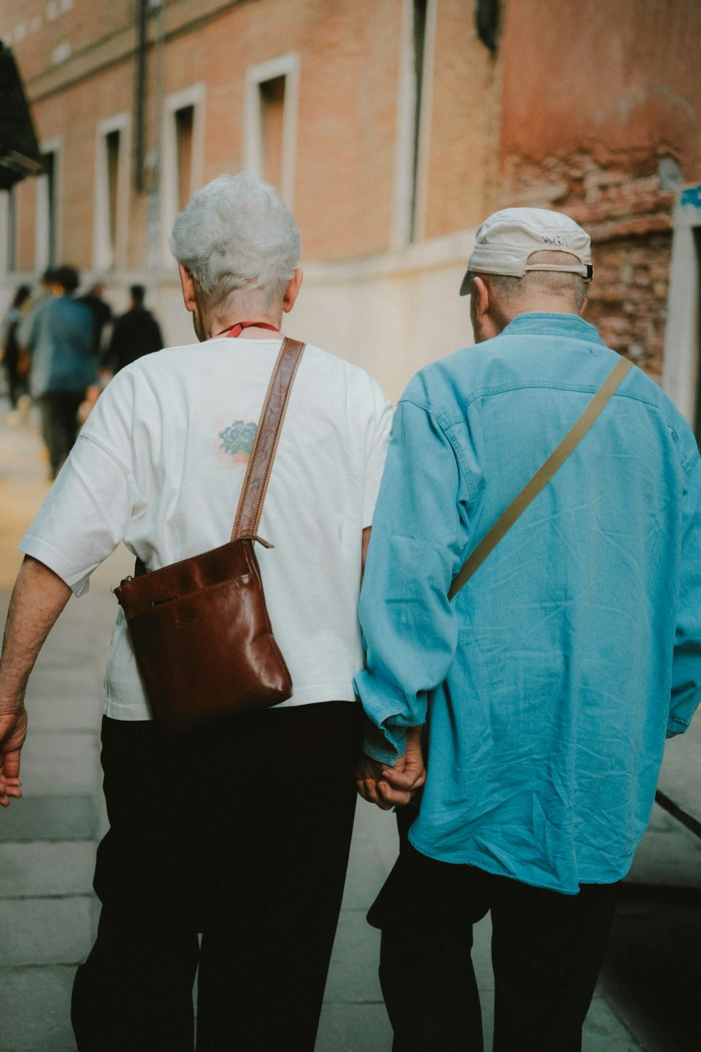 An older couple walking side by side, holding hands