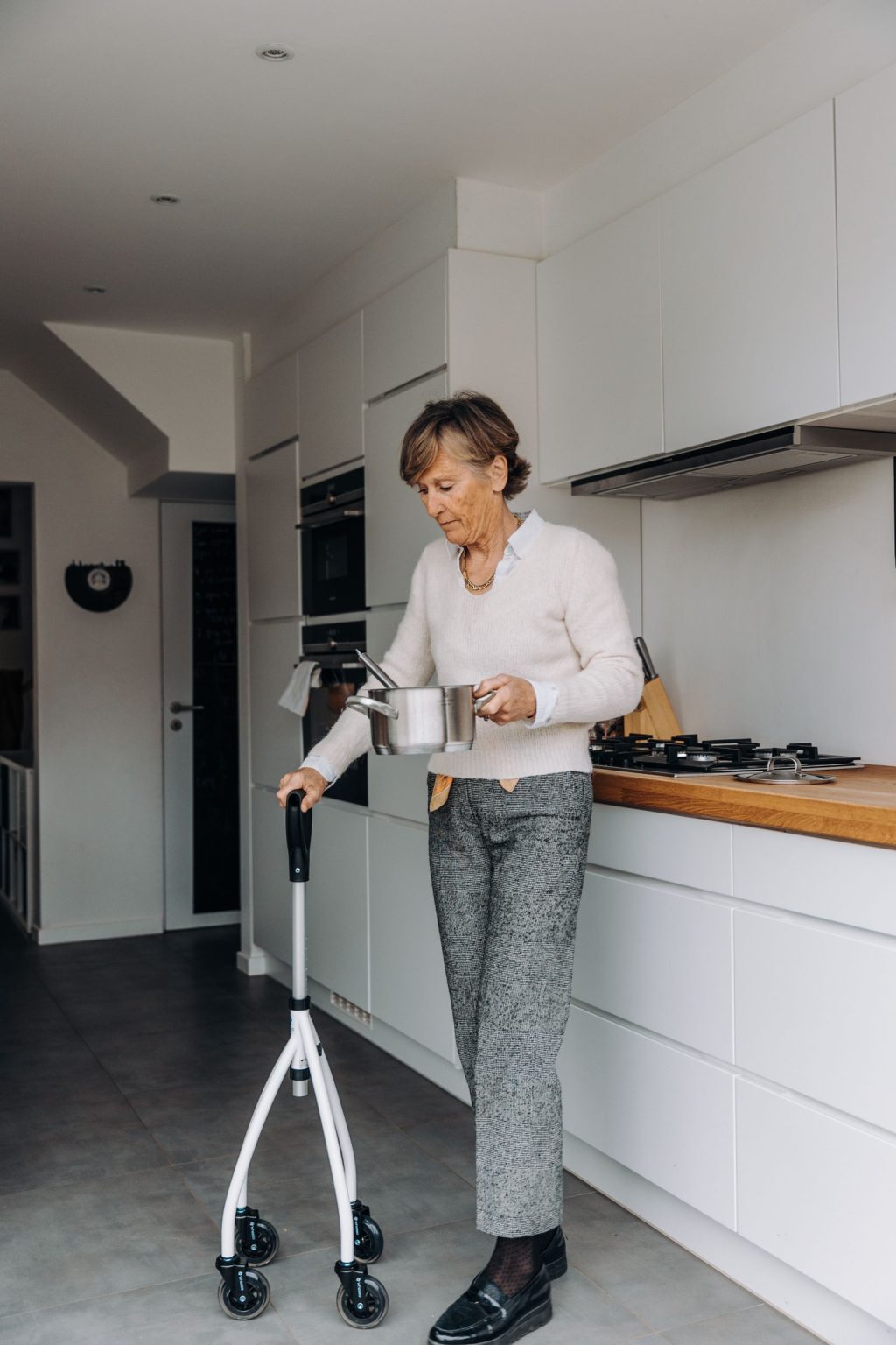 An older woman using a walker while cooking in her kitchen